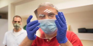 איתן סטיבה עם העדשה במעבדתו של פרופ' מורן ברקוביץ' בטכניון. צילום, רמי שלוש, דוברות הטכניון